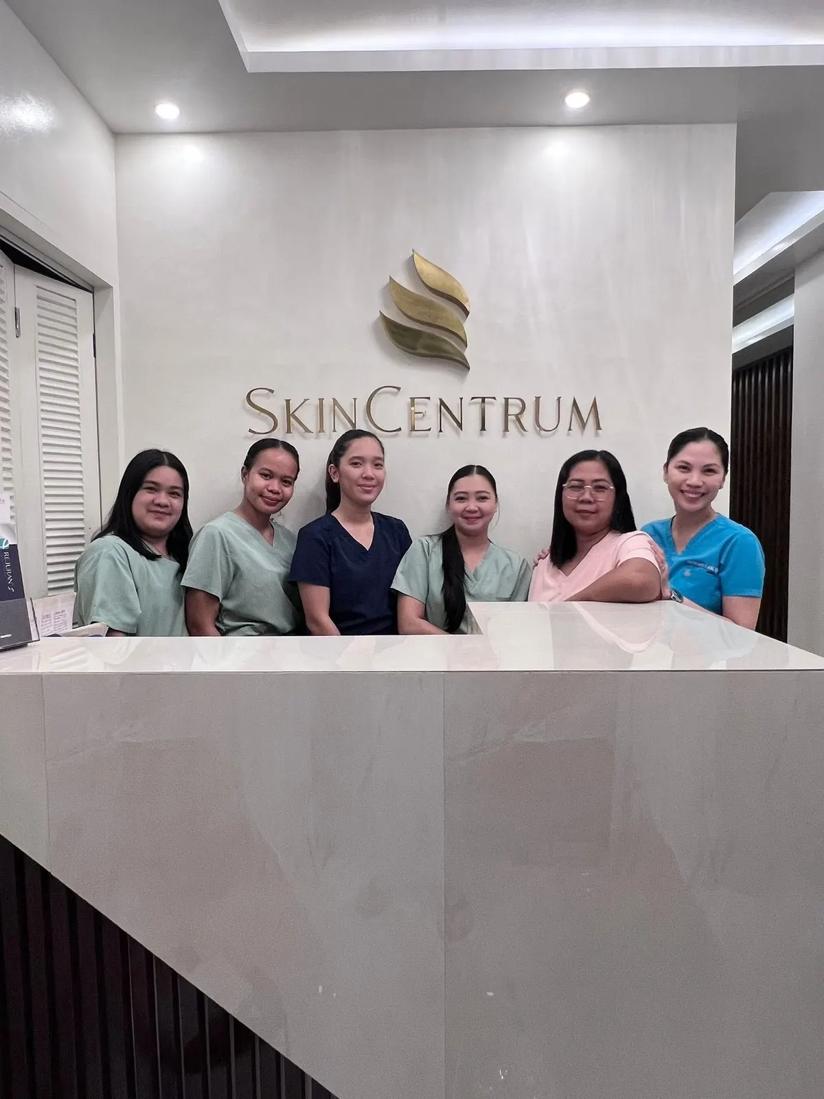 The SkinCentrum team standing at the clinic’s marble front desk under the SkinCentrum sign